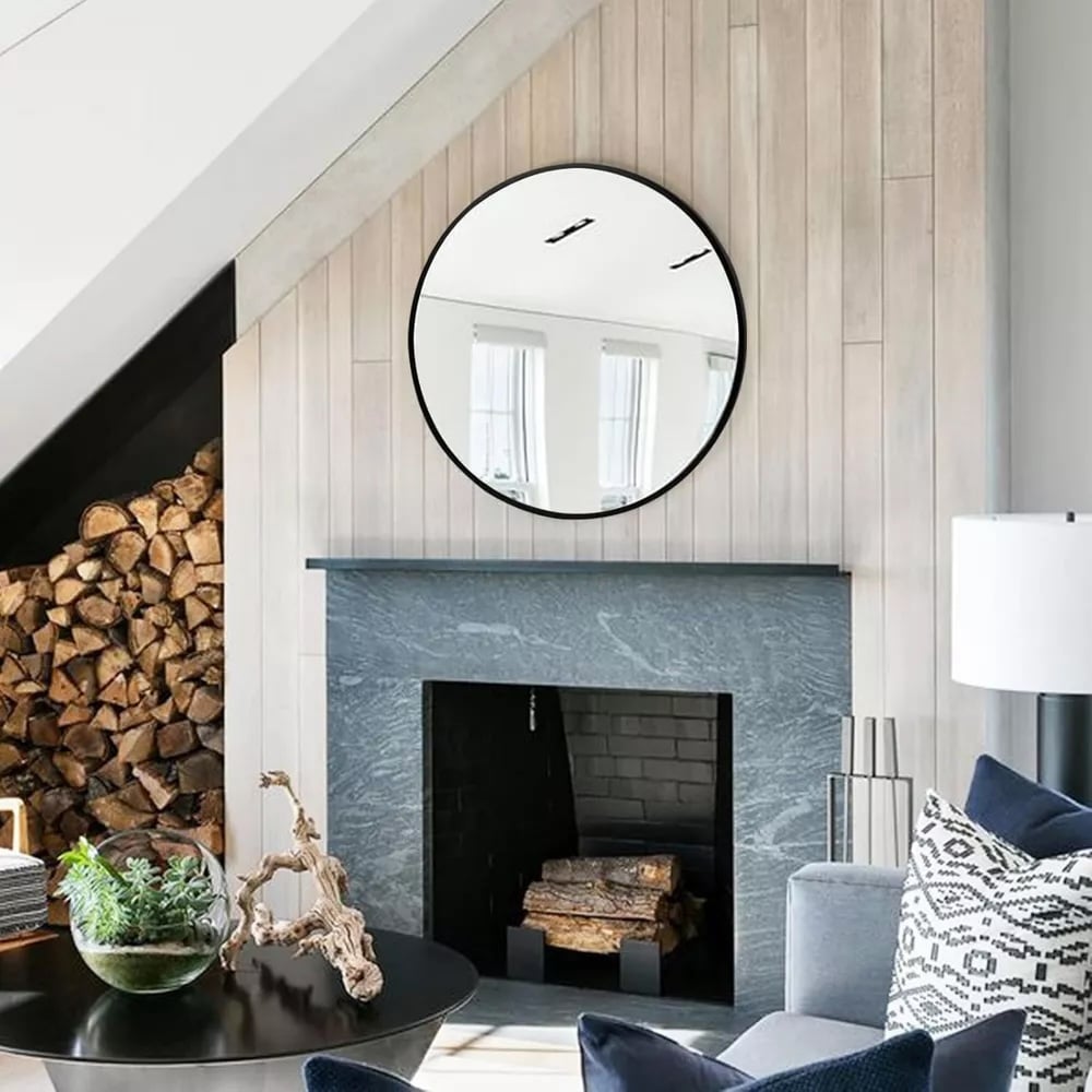 Round mirror above a marble fireplace.