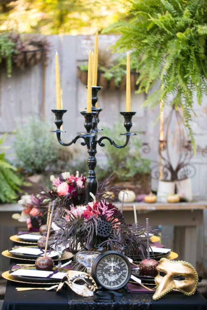 Idei de decor de Halloween Set de masă cu decor gotic elegant, inclusiv lumânări, măști de aur și flori.