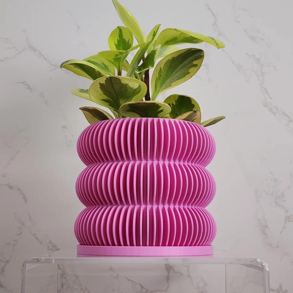 Ribbed Bubbles Planter in pink from Etsy sits on an acrylic side table.