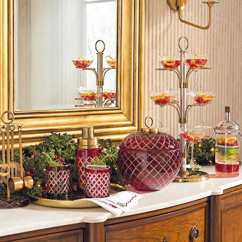 A buffet set up as a mini bar station with red holiday glassware, drinks, and napkins.