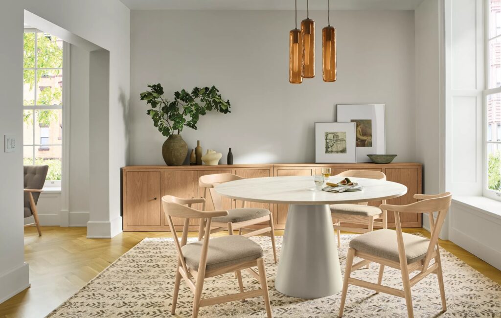 Round white dining table with four light wood chairs from Room & Board.