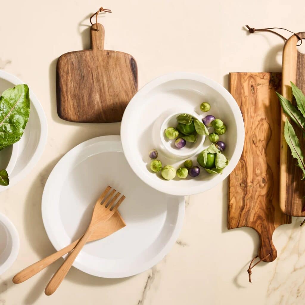 White stoneware serving platter on a table with bamboo utensils from our affordable kitchenware and serveware guide.