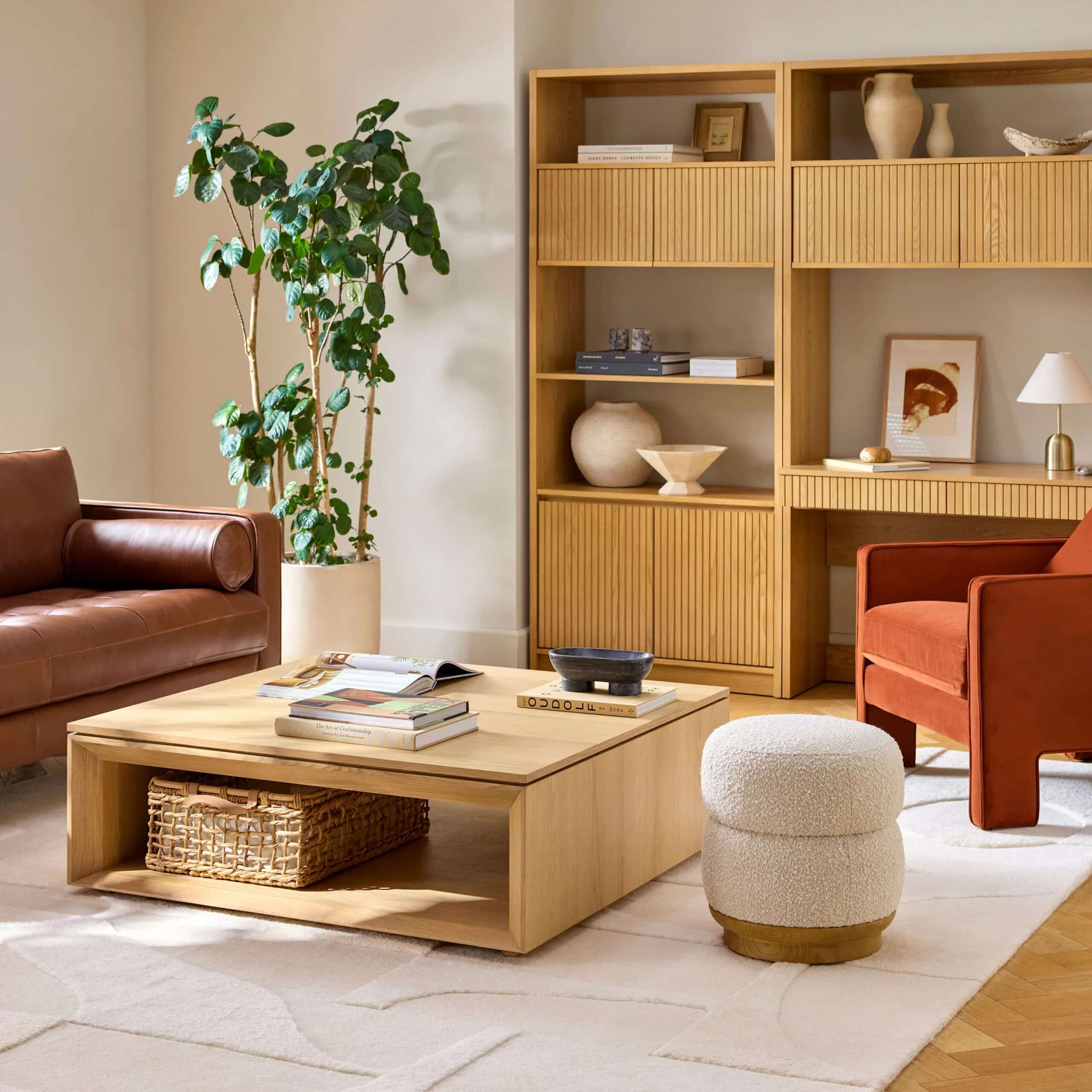 Square white oak storage coffee table centered in front of a brown leather sofa with balanced seating layout.
