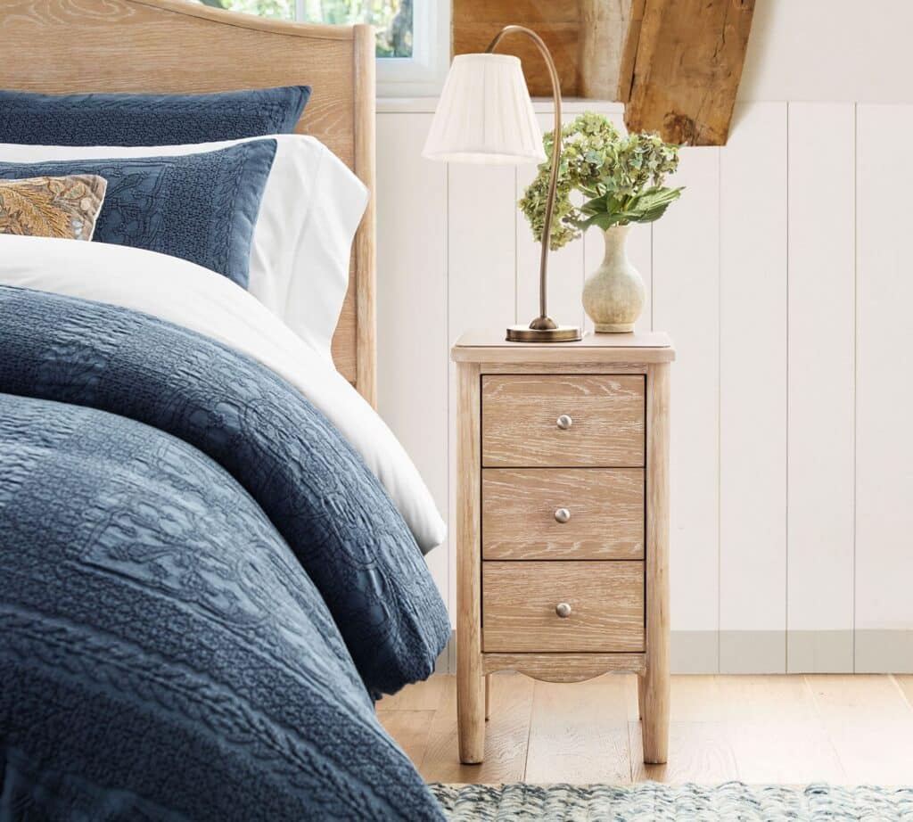 Bedroom with undersized nightstand lacking usable surface space next to the bed.