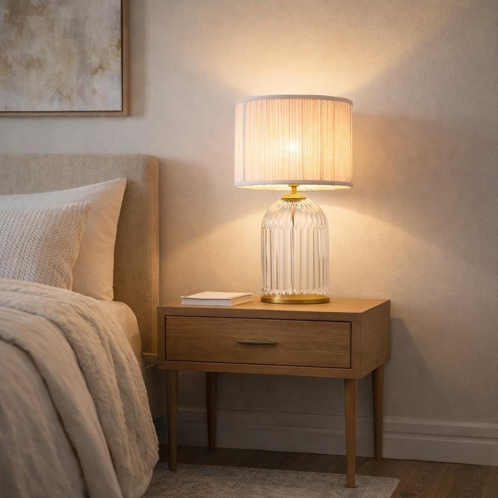 Glass table lamp with acrylic base styled on a bedside table.