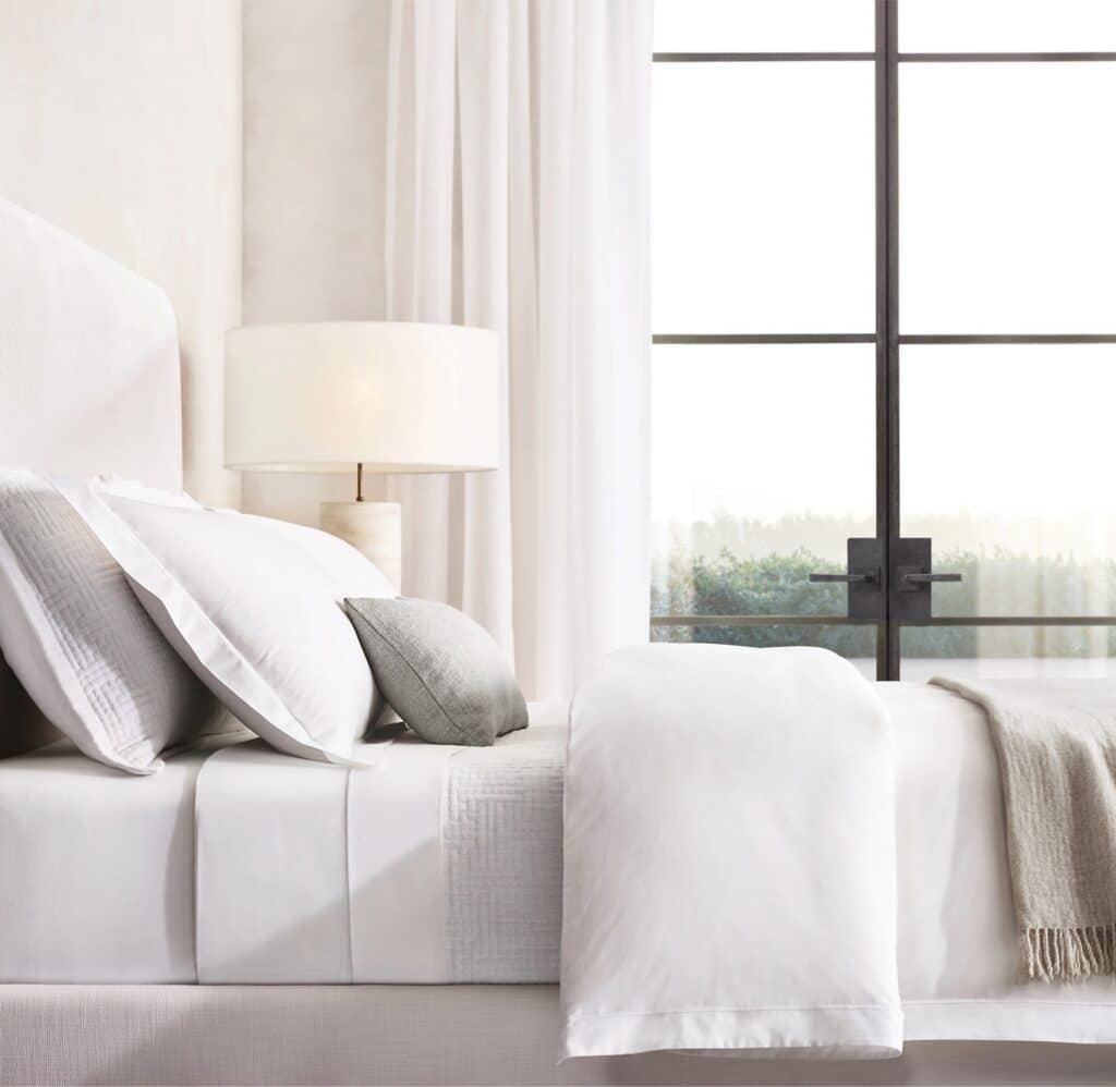 Luxury-inspired white summer bedding with layered linen textures and neutral accents.