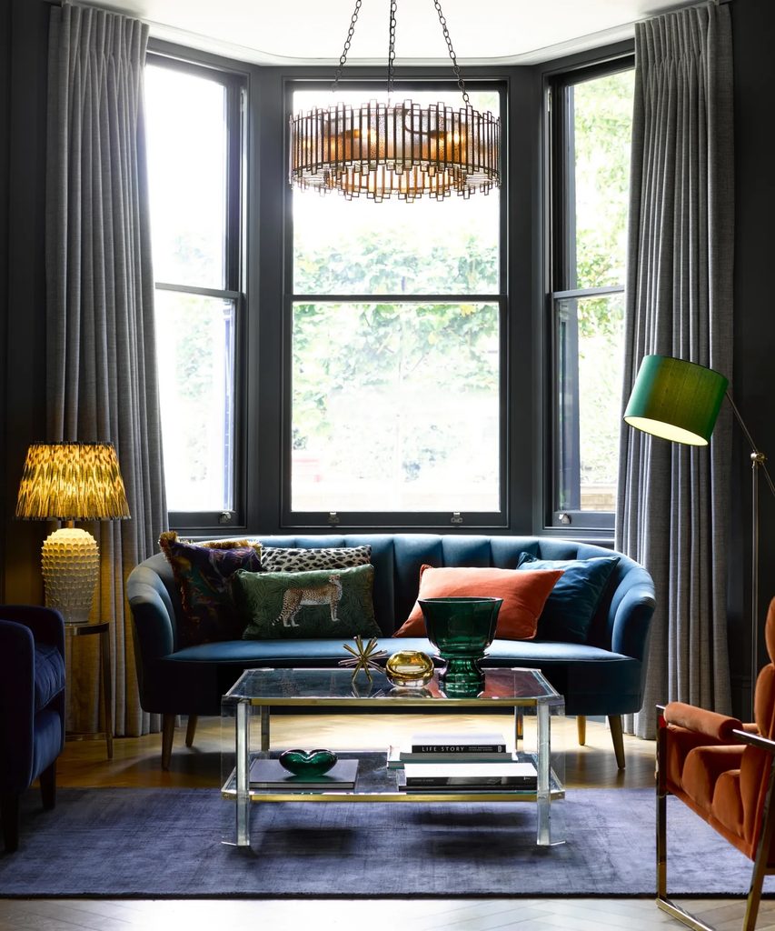 Living room with layered lighting from overhead fixture, table lamps, and a floor lamp around the seating area.